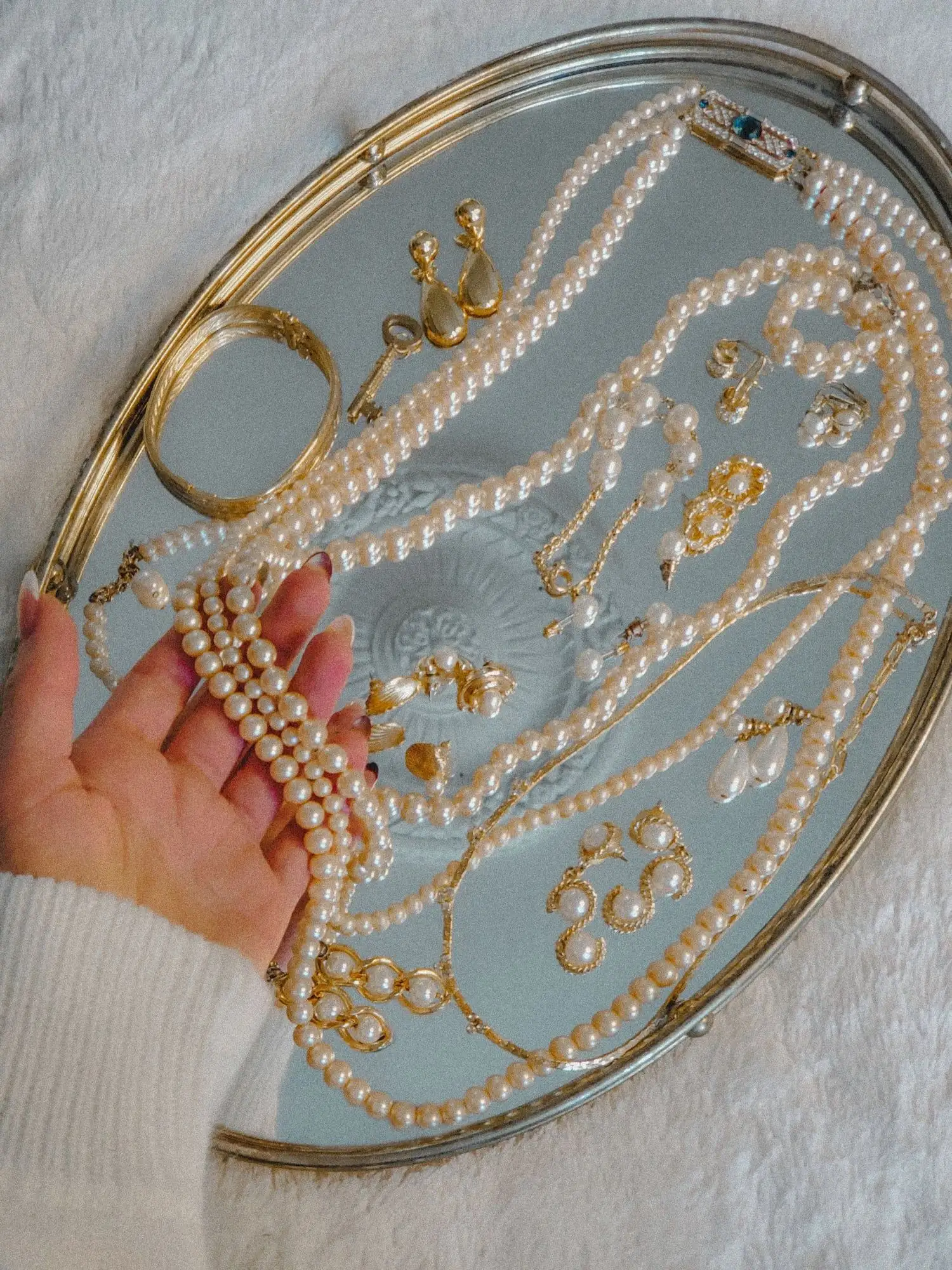 Colección de collares, aretes y pulseras de perlas exhibidos en una charola con espejo
