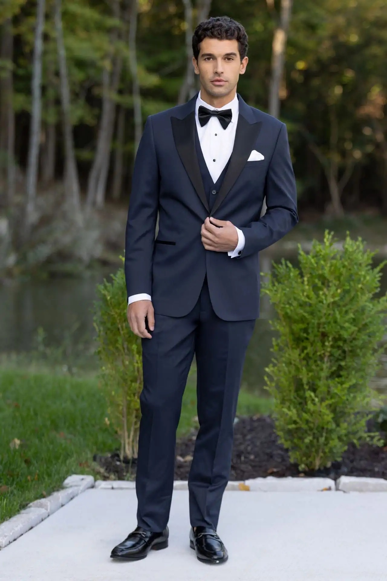 Traje azul marino Jim's Formal Wear con solapas de satín, chaleco a juego y moño negro