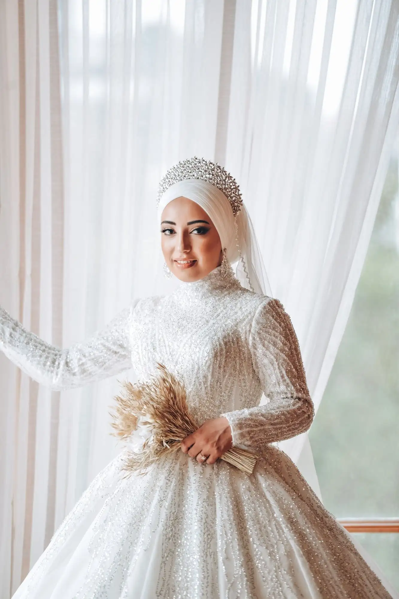Vestido de novia de cuello alto con lentejuelas y mangas largas, usado con hijab y tocado de pedrería
