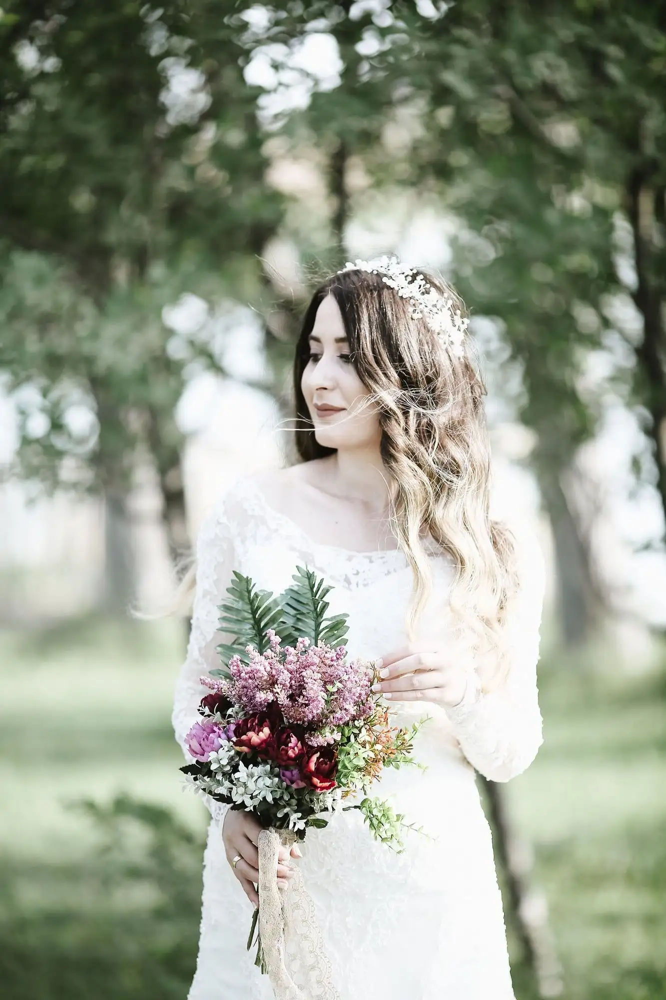 Vestido de novia de encaje con mangas largas, usado con corona de flores en un jardín