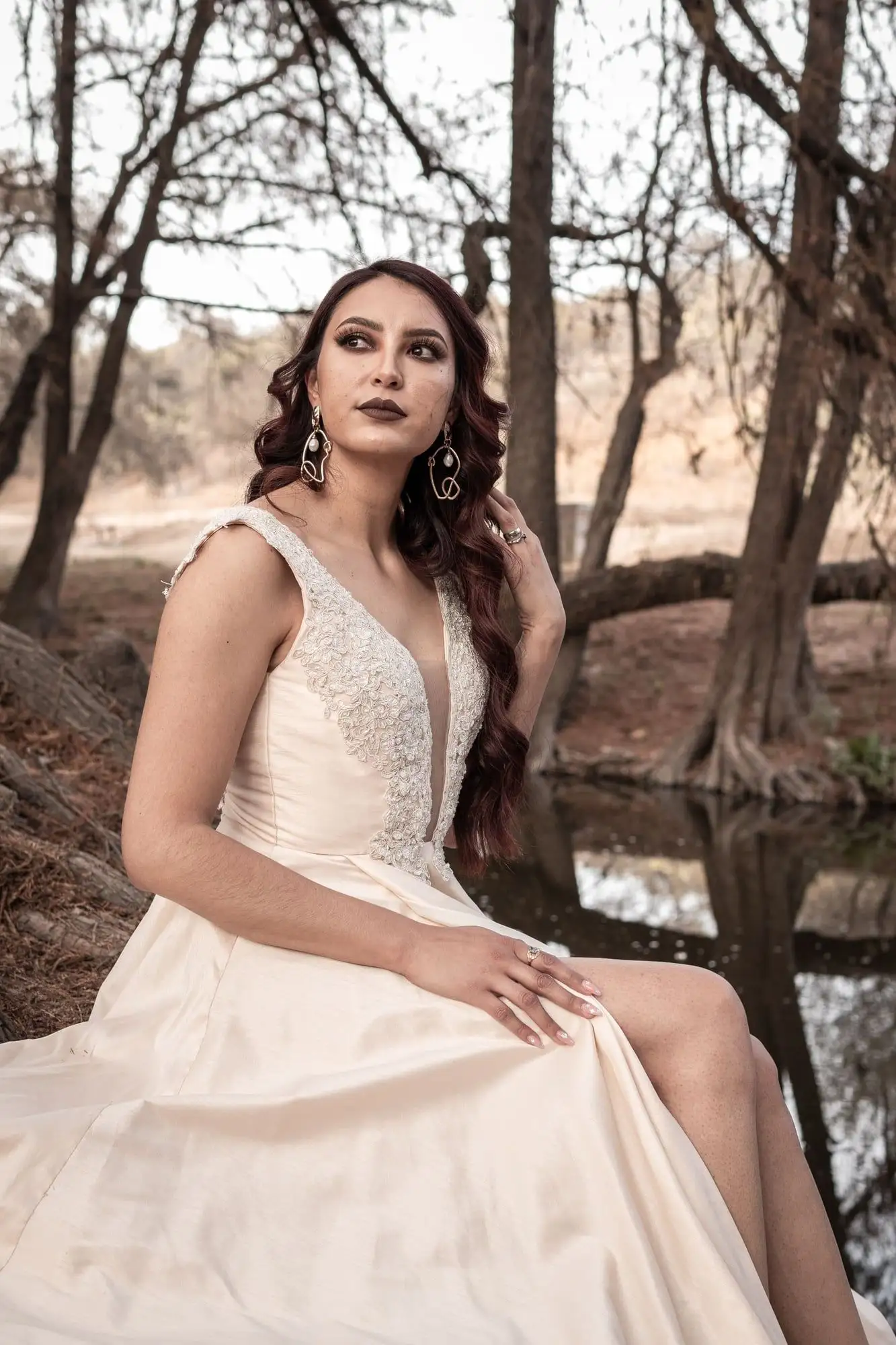 Vestido de novia color champán con cuerpo de encaje y escote profundo en V, junto a un estanque